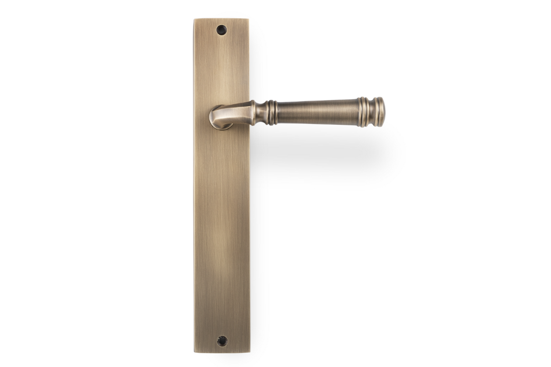 Product picture of the Apollo Design Tuscany Door Handle on Rectangle Plate Antique Brass Passage Set on a white background.