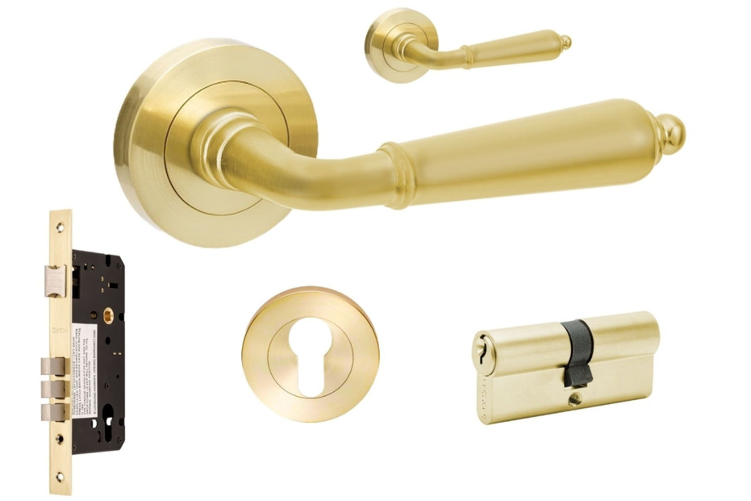 Gold door handle set with lock and key along with accessories on a white background.