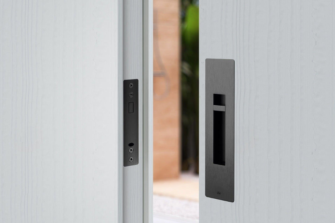 Image of the IN.20.925.TB Matt Black Sliding Door Privacy Kit installed on an off white door.