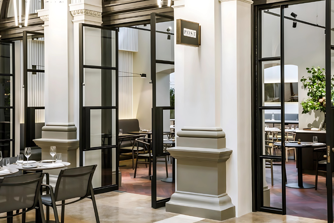 The The Zanda TS7004 EN-4 Floor Spring Hold Open Double Action Stainless Steel installed on cafe double doors leading out to a courtyard.