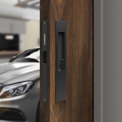 The Mardeco Sliding Door kit in matt black installed on a wooden door with a silver car blurred in the background.