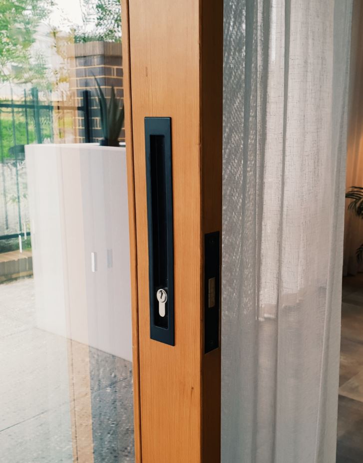 Insitu image of the Black sliding door lock kit on a brown wooden door.