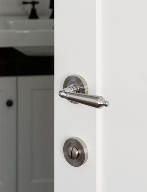 Insitu picture of the Round Privacy Kit installed on a white door with a lever handle above it.