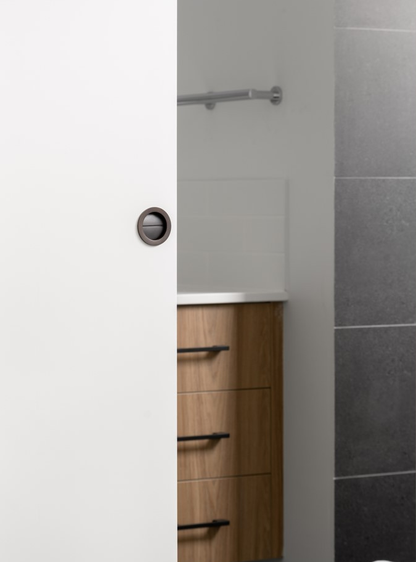 The 8106.GN Gun Metal Grey Sliding Door Privacy Kit installed on a white door with a bathroom ensuite in the background.