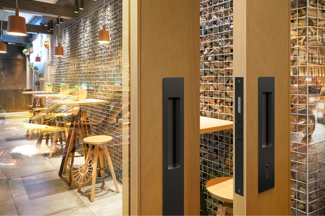 Insitu image of the BL8104/SET Matt Black Mardeco Flush Pull Euro Lockset installed on wood grain double doors with a alleyway restaurant in the background.