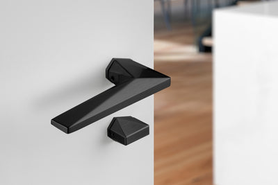 Archi Sketch Titanium Black PVD lever handle on a white door with a blurred background.