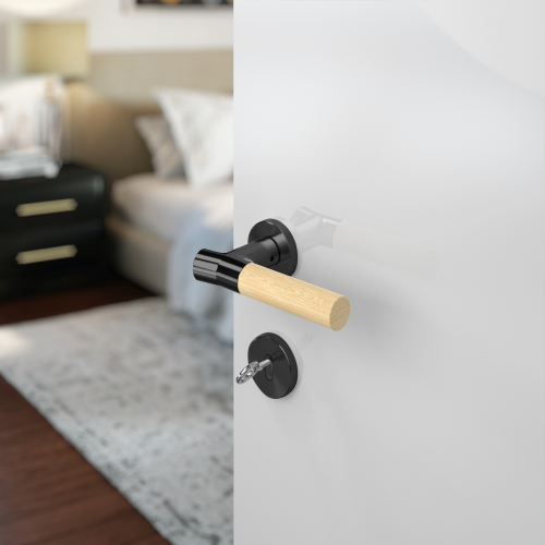 Insitu photo of the Wood Nature Matt Black Bamboo Door Handle on a white door with a bedroom blurred out in the background.