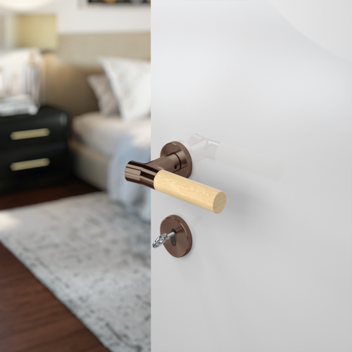 Insitu photo of the Wood Nature Antique Brass Bamboo Door Handle on a white door with a bedroom blurred out in the background.