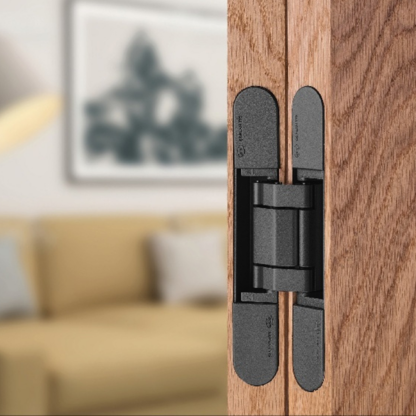 Insitu image of the IN.05.061.B 3D Adjustable Concealed Hinge 150 Black installed on a wooden door with a blurred out lounge room in the background.