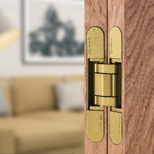 Insitu image of the IN.05.061 Coplan Gold hinge installed on a wooden door with a blurred background.