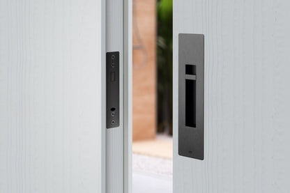 Close-up of a modern door handle and lock mechanism on a light gray door.