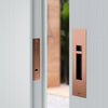 Image of the IN.20.925.TCO Copper Sliding Door Privacy Kit installed on an off white door.
