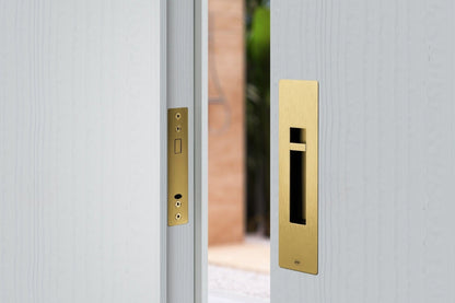 The Red Dot Design Award Winning Pendulum Sliding Door Privacy Kit in Satin Brass installed on an off white door.