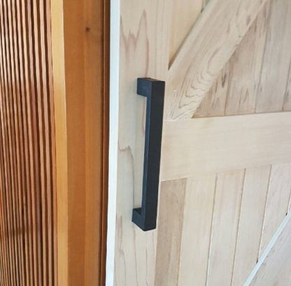 The 300mm Ultra Matt Black Pull Handle installed on a wooden barn door.