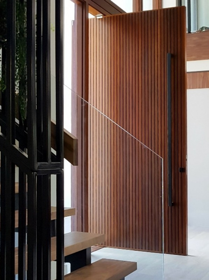 The Ultra Matt Black pull handle in 1800mm installed on a wooden door with a staircase in the foreground.