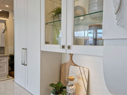 Brushed Nickel Manhattan cabinet knobs installed on white cabinets with glass in the door as well.