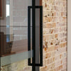 The Toorak Matt Black pull handle installed on a glass door.