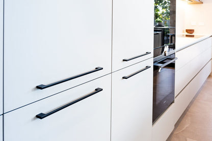 Insitu image of the Urban Matt Black Cabinet Handle installed on white cabinetry.